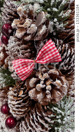 Frosted pine cones, red gingham bow, and berries creating a rustic Christmas background 133361184