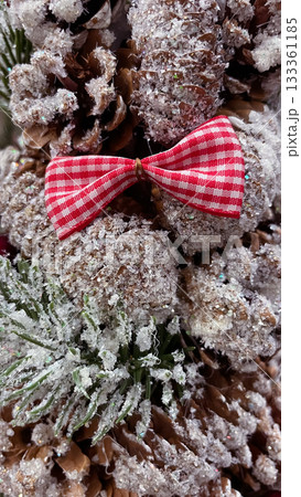 Frosted pine cones, red gingham bow, and berries creating a rustic Christmas background 133361185