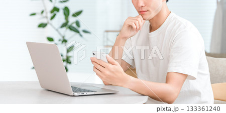 パソコンとスマホを使う若いアジア人男性（投資,マネーリテラシー,資産形成,資産管理） 133361240