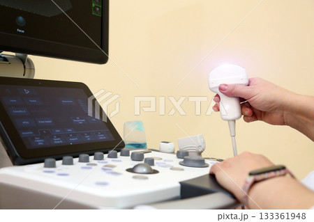Modern ultrasound device. Ultrasound examination of internal organs. A woman undergoing an ultrasound scan of her abdominal cavity. Ultrasound examination device. Modern ultrasound device. Ultrasound examination of internal organs. A woman undergoing an ultrasound scan of her abdominal cavity. Ultrasound examination device. 133361948