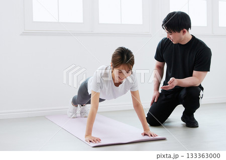 パーソナルトレーナーにトレーニングを受ける若い女性 133363000