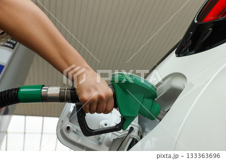 Hand with nozzle refueling a vehicle at a service station Hand with nozzle refueling a vehicle at a service station 133363696