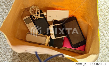 紙袋に入ったたくさんのスマホや携帯電話 133364104
