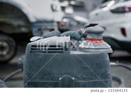 An orbital polisher in a garage shows a close-up of a dusty sander on car bodywork An orbital polisher in a garage shows a close-up of a dusty sander on car bodywork 133364135
