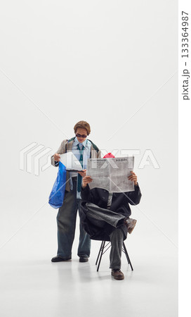 Two men in retro inspired outfits reading documents symbolizing creative leadership and reflection Two men in retro inspired outfits reading documents symbolizing creative leadership and reflection 133364987