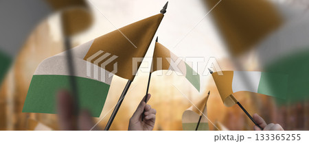 Cote dIvoire flags in their hands on a blurred urban background Cote dIvoire flags in their hands on a blurred urban background 133365255