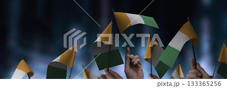 Cote dIvoire flags in their hands on a blurred urban background 133365256