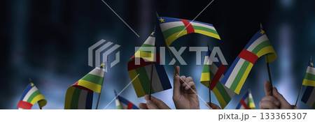 Central African Republic flags in their hands on a blurred urban background 133365307