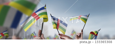 Central African Republic flags in their hands on a blurred urban background 133365308
