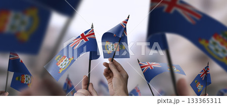 Cayman Islands flags in their hands on a blurred urban background 133365311