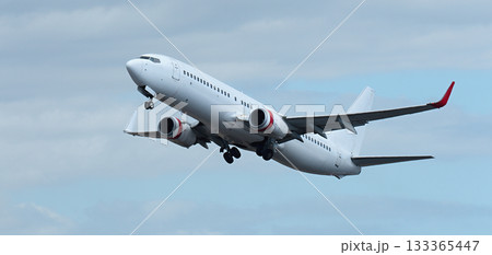 Airplane take off on the blue sky, with white clouds. Aircraft flying on sky background. White passenger jet plane in the blue sky. Low angle view of Airplane flying under blue sky, with white clouds 133365447
