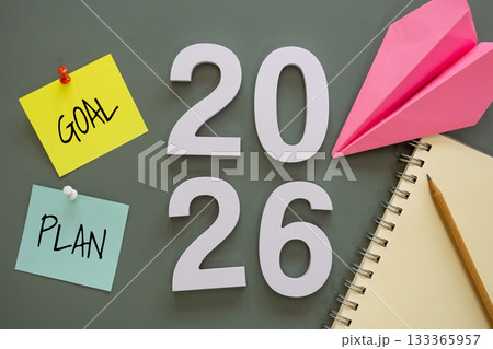 number of New Year 2026 with word goal and plan on post-it paper pin on green background, notebook, and paper plane symbolize New Year targets, resolutions, strategy, progress, and fresh starts. 133365957