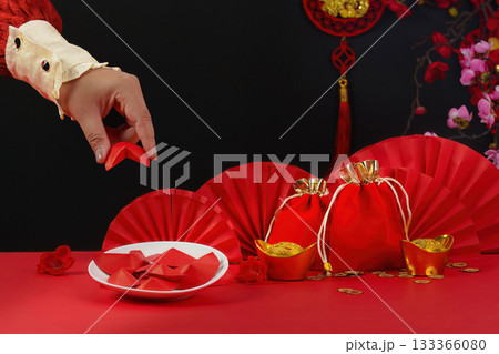 Lunar New Year tradition. Hand placing red envelope on festive table. Lunar New Year tradition. Hand placing red envelope on festive table. 133366080