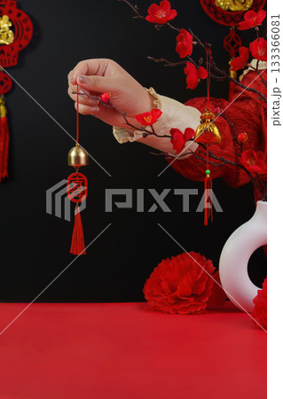 Lunar New Year charm. Hand holding decorative bell with red tassel. 133366081