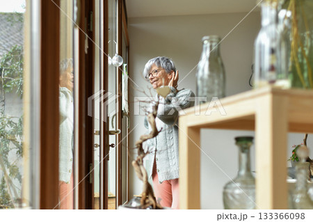 A 75-year-old gray-haired woman looks out the window A 75-year-old gray-haired woman looks out the window 133366098