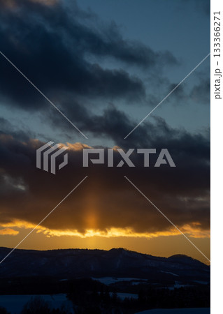 冬の山から伸びる太陽柱 133366271
