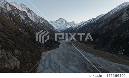 Majestic snow-capped mountains towering over winding river valley landscape 133366502