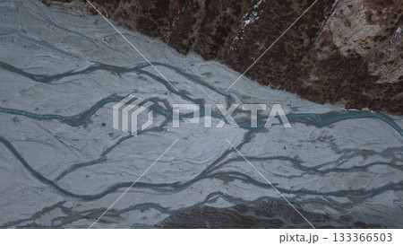 Aerial view of winding river flowing through rocky terrain and forest 133366503