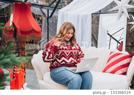 Photo of satisfied positive young 30s woman sitting at home on sofa using laptop browsing, find new year gift cheap price indoors 133366524