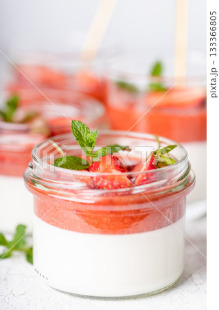 Panna cotta in glass jar with strawberry sauce and mint leaf. 133366805