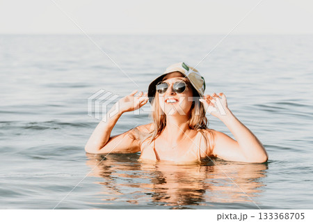Woman, Beach, Water - Happy woman wearing sunglasses and a hat in the ocean. Woman, Beach, Water - Happy woman wearing sunglasses and a hat in the ocean. 133368705