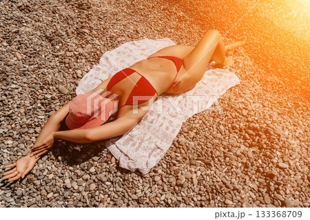 Beach Sunbathing Woman Relaxation - Woman in red bikini sunbathing on beach towel in the sun. 133368709