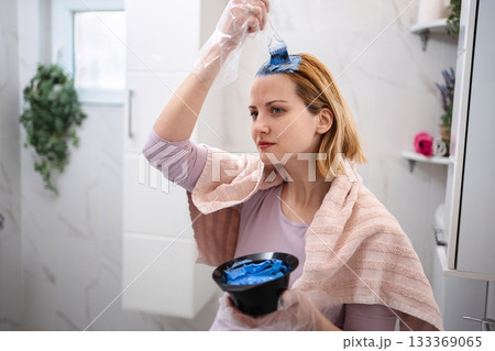 Woman dyeing her hair blue in the bathroom 133369065