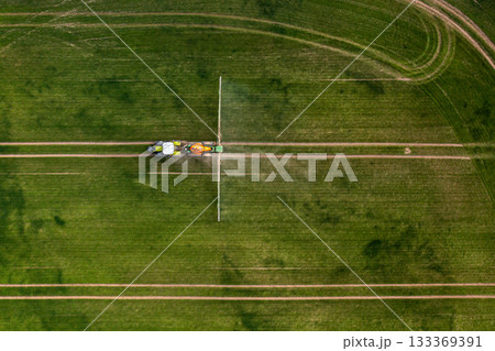 aerial view of the tractor spraying the chemicals on the large green field aerial view of the tractor spraying the chemicals on the large green field 133369391