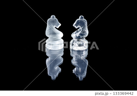 two opponent glass chess knights with reflection isolated on a black glass background 133369442