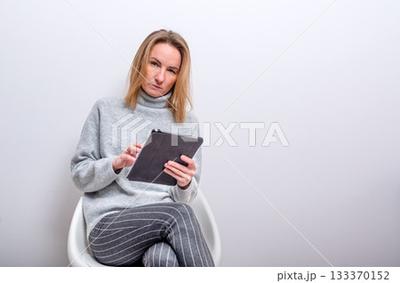 blond woman with glasses and tablet in hands, remote working concept, isolated on gray blond woman with glasses and tablet in hands, remote working concept, isolated on gray 133370152