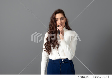 attractive female conference speaker during presentation, holds microphone and makes some gestures 133370281