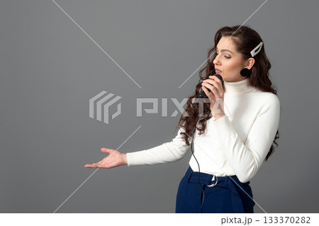 attractive female conference speaker during presentation, holds microphone and makes some gestures 133370282