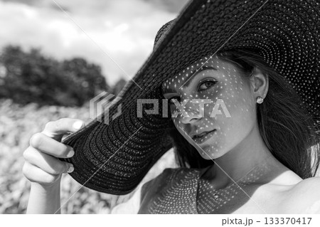 monochrome portrait of beautiful woman in elegant hat, pattern of shadows falling on her face monochrome portrait of beautiful woman in elegant hat, pattern of shadows falling on her face 133370417