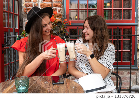 two cheerful charming young women talking and laughing in outdoor cafe, girls party concept 133370720