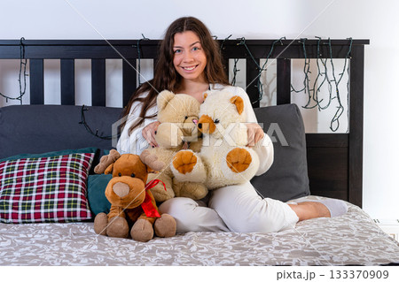 nice attractive woman sitting in bed hugging her soft childhood toys 133370909