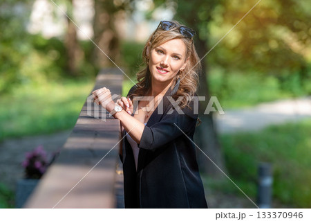 fashion portrait of a stylish nice blonde female in sunglasses leaning on a railing of pedestrian bridge 133370946