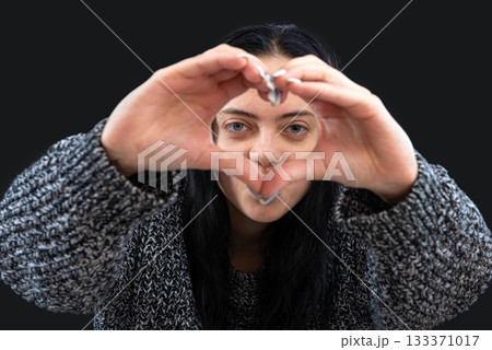 woman with long dark hair making heart shape hand gesture and looking at camera, isolated on black woman with long dark hair making heart shape hand gesture and looking at camera, isolated on black 133371017