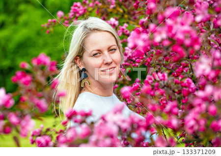 closeup portrait of a smiling blonde woman in a blossoming garden in spring, selective focus 133371209