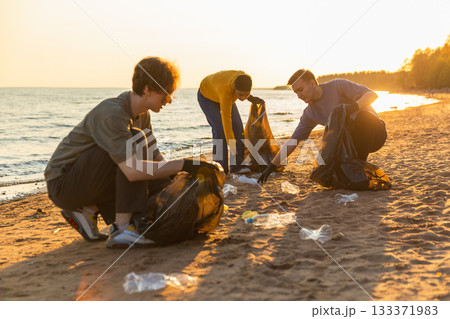 Earth day. Volunteers activists team collects garbage cleaning of beach coastal zone. Woman mans puts plastic trash in garbage bag on ocean shore. Environmental conservation coastal zone cleaning Earth day. Volunteers activists team collects garbage cleaning of beach coastal zone. Woman mans puts plastic trash in garbage bag on ocean shore. Environmental conservation coastal zone cleaning 133371983