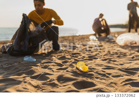 Earth day. Volunteers activists collects garbage cleaning of beach coastal zone. Woman mans with trash in garbage bag on ocean shore. Environmental conservation coastal zone cleaning. Blurred image 133372062