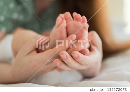 Happy family. Tiny newborn infant male or female baby feet on mother hands. Mother holding newborn child. Mom and her baby. Maternity tenderness parenthood new life concept. Handle with care Happy family. Tiny newborn infant male or female baby feet on mother hands. Mother holding newborn child. Mom and her baby. Maternity tenderness parenthood new life concept. Handle with care 133372078