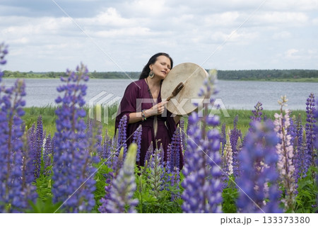 Shaman woman drumming among blooming flowers Shaman woman drumming among blooming flowers 133373380