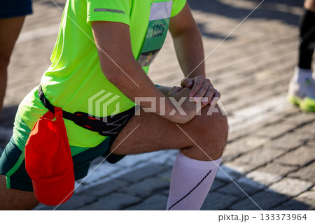 Athlete runner warming up his legs before marathon run Athlete runner warming up his legs before marathon run 133373964