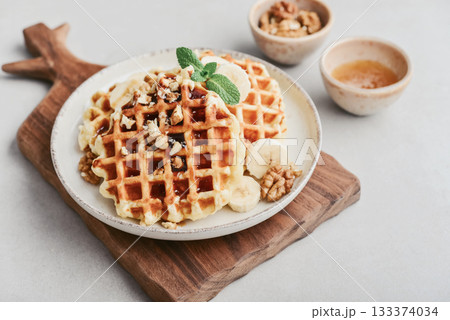Homemade waffles with topping of honey, walnut and banana Homemade waffles with topping of honey, walnut and banana 133374034