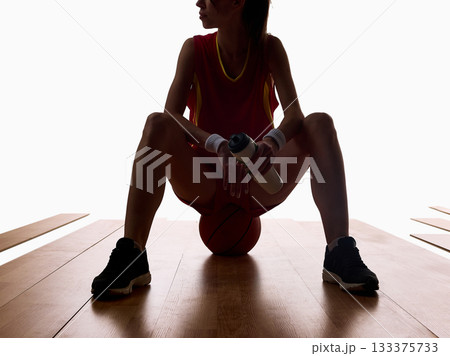 Basketball player sitting with water bottle and ball after workout 133375733