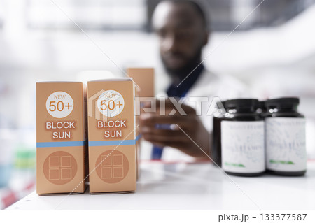 Pharmacist arranging pills and checking inventory on pharmacy shelves, managing storage and preparation of apothecary products for professional care and wellness support. Efficiency. 133377587