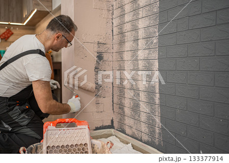 Man Painting Brick Wall With Paint Roller Man Painting Brick Wall With Paint Roller 133377914