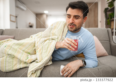 Man Sitting on a Couch Holding a Drink Man Sitting on a Couch Holding a Drink 133377922