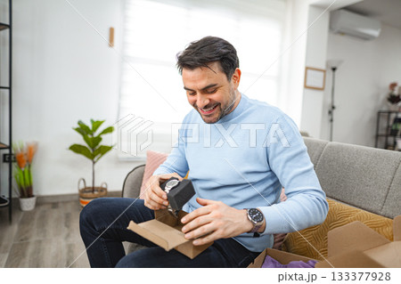 Man has opened the package and is looking at the new watch Man has opened the package and is looking at the new watch 133377928