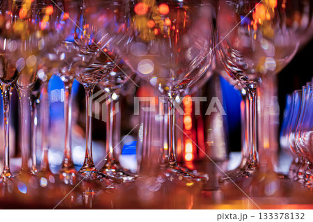 Elegant scene of wine being poured into glasses aligned in a row, showcasing the rich colors and graceful flow of the liquid, set against a dark, warm background, ideal sophisticated dining settings Elegant scene of wine being poured into glasses aligned in a row, showcasing the rich colors and graceful flow of the liquid, set against a dark, warm background, ideal sophisticated dining settings 133378132